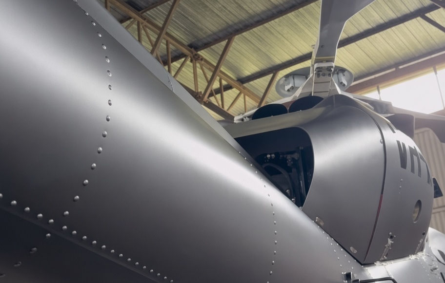 Close-up of a silver aircraft fuselage and exterior panels inside a hangar.
