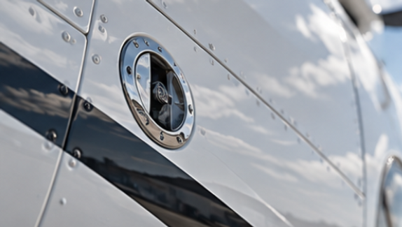 Close-up of a white aircraft fuselage showing its polished finish, panel lines and dark stripe.