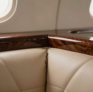 Cream leather aircraft seating beside polished wood veneer.