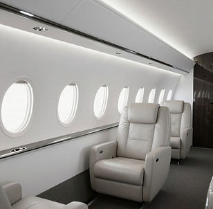 Aircraft cabin with cream leather seating, oval windows and light-coloured interior panels.